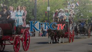 Two horse-drawn buggies with women in pioneer dresses at Cheyenne Frontier Days parade.